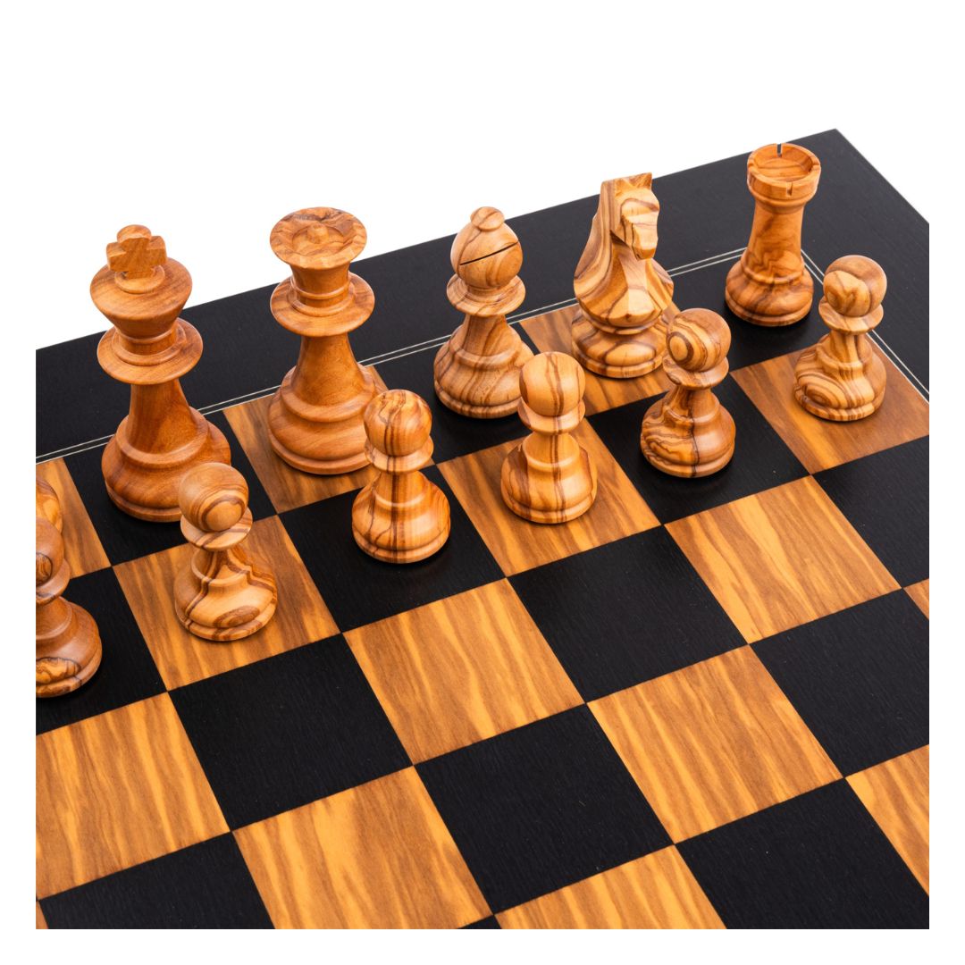 ljusa schackpjäser i olivträ placerade på sina startpositioner, handgjorda i olivträ