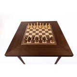 Schackbräde och schackbord i valnöt sett ovanifrån med pjäser i schackuppställning strax innan det första draget spelas