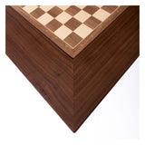 Hörnet av ett schackbord med schackbräde båda i valnöt infattade i. Bordet är något mörkare än schackbrädet