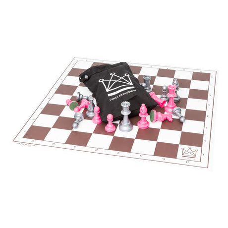 Schackspel med schackpjäser i silver och rosa tillsammans med en svart schackväska med Dansk skoleskak-logotypen tryckt på mitten av schackbrädet