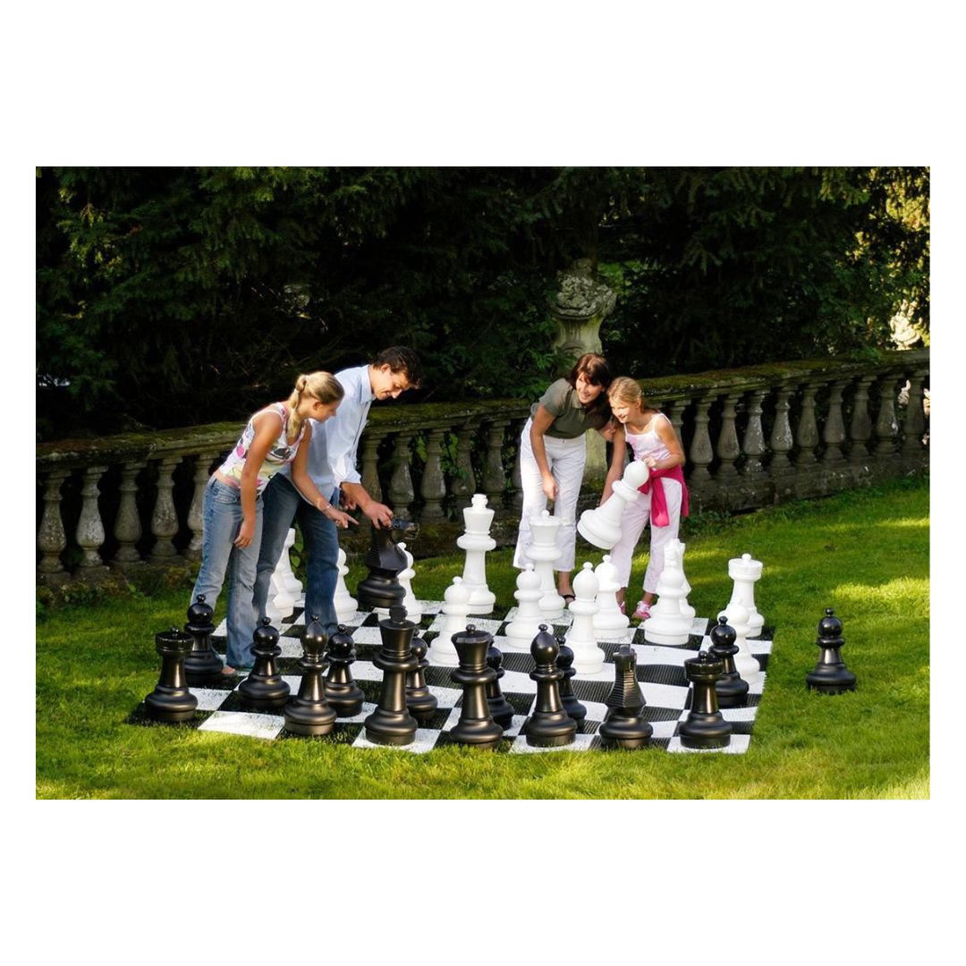 Familj som spelar jätteschack i trädgården en solig dag