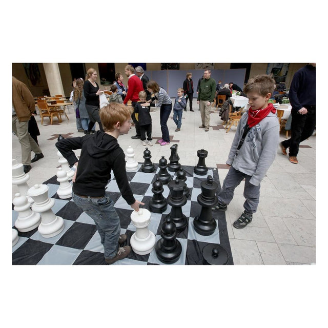 Stora schackpjäser används för ett evenemang i stadshuset av två pojkar i en kreativ miljö